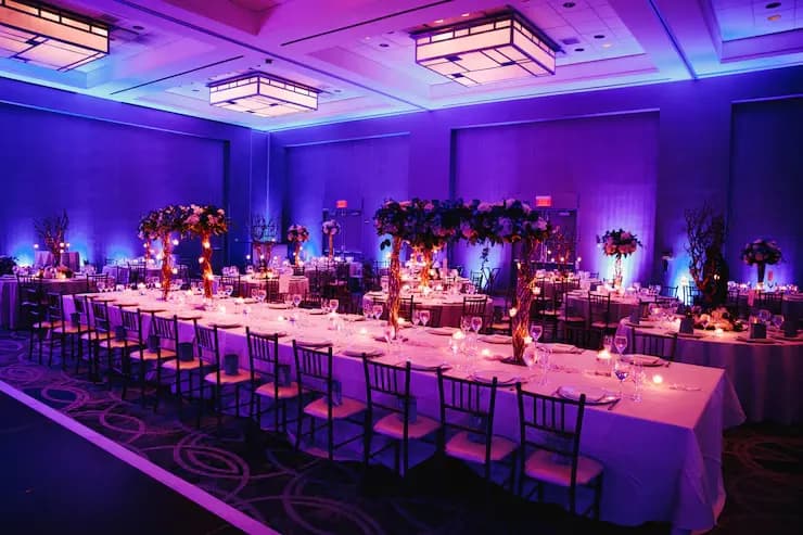 Elegant banquet hall setup with floral centerpieces and purple lighting