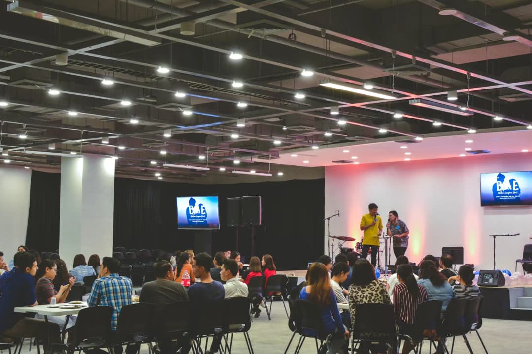 Conference room with stage setup and attendees seated in round tables
