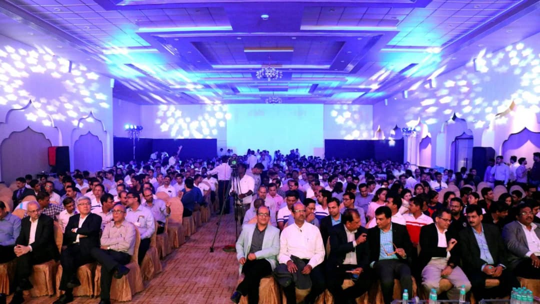 Audience attending a large corporate conference with blue-themed lighting